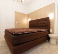 Bedroom in a 3-room apartment with a brown bed and a white table, carpet.