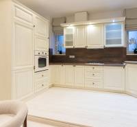 The kitchen in a 3-room apartment with a cream kitchen unit and a white floor with a wooden decor.