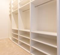 Spacious wardrobe with white shelves and hanging rods in a 3-room apartment.