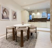 Dining area in a 3-room apartment with a round table, chairs, and abstract paintings.