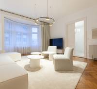 Living room with wood-patterned flooring, sofa, tables in a three-room apartment.