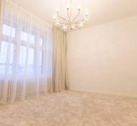 A room in a 3-room apartment with a chandelier, curtains, and a light carpet.