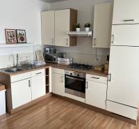 Kitchen in a 2-room apartment with wooden floor decor, kitchen cabinets, stove, and accessories.
