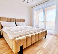 A bedroom in a 3-room apartment with a light bed and a floor with a wooden decor.