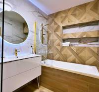 Bathroom with wood-patterned flooring, mirror, and shower in a 3-room apartment.