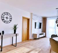 Living room in a three-room apartment with a wooden decor floor, table, and television.