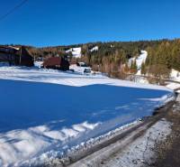 Snow-covered residential lands in Ždiar, set in a mountainous landscape with wooden cottages.