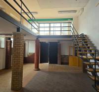 Commercial spaces with wood-patterned flooring and a staircase next to brick pillars.