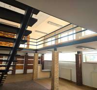 Interior commercial spaces with wood-patterned flooring and metal staircase.