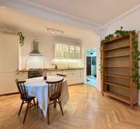A kitchen in a 2-room apartment with a wooden decor floor, dining table, and shelf.