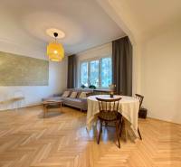 Living room in a two-room apartment with a brown sofa and a wooden decor floor.