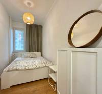 A room with a bed, a mirror, and decorative lighting in a 2-room apartment.