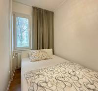 Bedroom in a 2-room apartment with a bed, window, and curtains, floor with wooden decor.