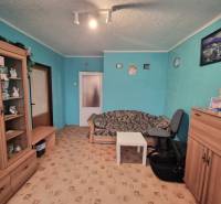 A room in a 3-room apartment with turquoise walls, brown furniture, and a patterned carpet.