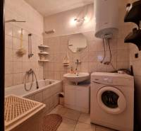 Bathroom in a 3-room apartment with a bathtub, washing machine, and gas water heater.