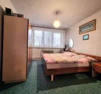 Bedroom in a 3-room apartment with a double bed, carpet, furniture, and curtains on the window.