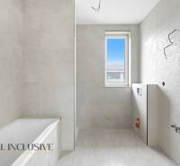 Bathroom in a family house with a bathtub, window, and light tiles.