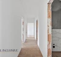 A hallway in a family house with white walls and a wooden-patterned floor.