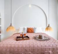 A bedroom in a villa with a comfortable bed, decorative pillows, and hanging lamps.