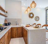 Interior of a villa with a kitchenette, wooden cabinets, and decorative mirrors.