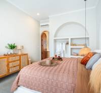 A bright bedroom in a villa with natural decorations, soft lighting, and a comfortable bed.
