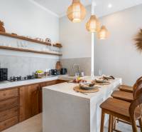 A villa kitchen with stylish wooden elements, bar stools, and pendant lamps.