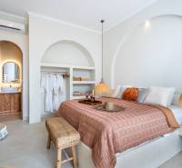 Bright bedroom in a villa with a double bed, lamp, and open wardrobe.