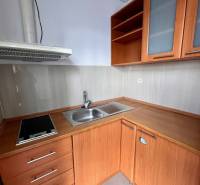 Kitchen unit in offices with a cooktop and cabinets with wooden decor.