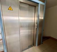 Stainless steel elevator in offices with tiled flooring.