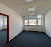Offices with carpeted floors, large windows, white walls, coffered ceiling.
