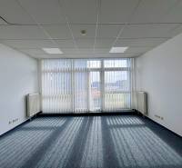 Offices with carpeted floors and large windows, providing a bright workspace.
