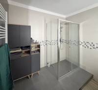 A bathroom in a 3-room apartment with a large shower and storage space.
