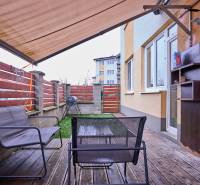 Terrace in a 2-room apartment with a wooden decor floor, outdoor seating, and an awning.