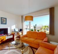 Living room in a two-room apartment with an orange sofa and a TV, floor with wooden decor.