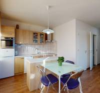 A kitchen in a 2-room apartment with a wood-patterned floor and a table with chairs.