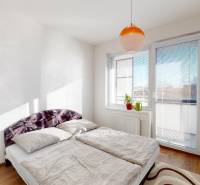 A bright bedroom with a large bed, a window, and a wooden decor floor in a 2-room apartment.