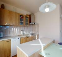 A kitchen in a 2-room apartment with a wooden decor, equipped with appliances and lighting.
