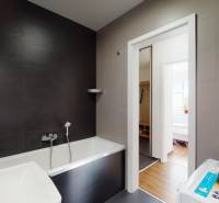 Bathroom in a two-room apartment with a bathtub and a washing machine, floor with wood decor.