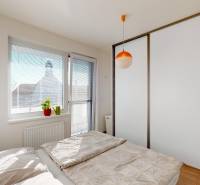 Bedroom with a sliding wardrobe and a bed in a 2-room apartment, floor with wooden decor.