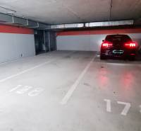 Underground garage with a car, an empty parking space, and concrete walls.