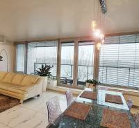 Living room in a three-room apartment with a light sofa, table, and glass doors.
