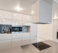 A kitchen in a 3-room apartment with glossy white cabinets and built-in appliances.