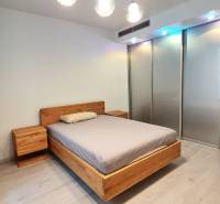 Bedroom with a wooden bed, nightstands, and a floor with a wood decor in a 3-room apartment.