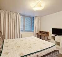 A bedroom in a three-room apartment with a bed, a television, and a writing desk.