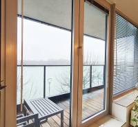 A balcony with a view of the river, glass doors, floor with wooden decor.