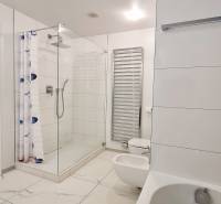 Bathroom with a bathtub, shower, and toilet in a three-room apartment. White tiles.