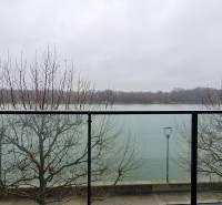 A view from a 3-room apartment of the river and trees through glass railings.