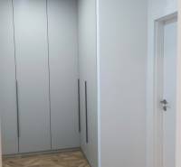 A hallway with white built-in wardrobes and a floor with a wooden decor in a 4-room apartment.
