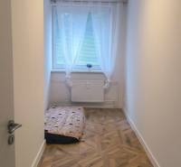 A narrow room with a large window and a wooden decor floor in a 4-room apartment.