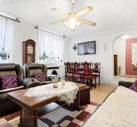 Living room of a family house with a fireplace, black sofas, and a floor with a wooden decor.